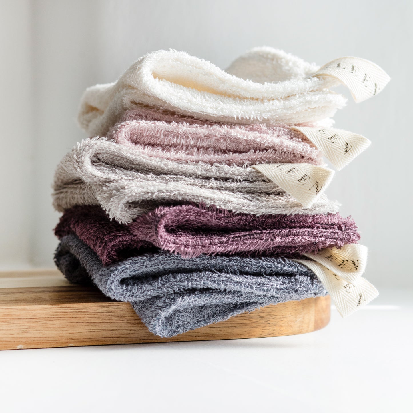 Stack of folded textured socks on a wooden board with a light background